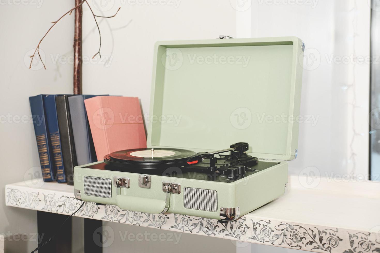 retro style home vinyl disk player or turntable. portable device for LP disk listening. retro music. vintage books on a shelf. photo