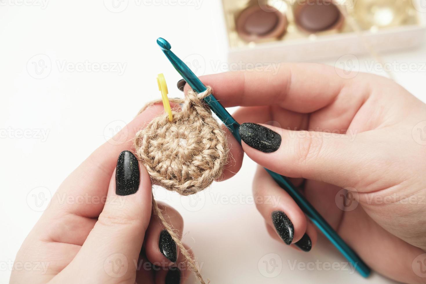 manos de una mujer sosteniendo crochet hilo de yute y fragmento de un patrón de