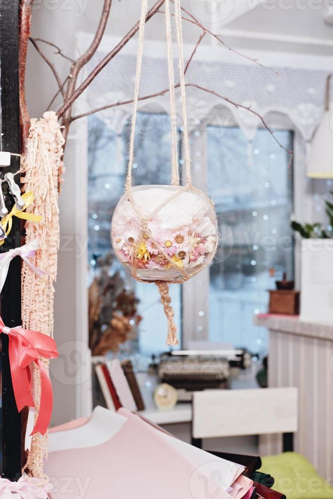 part of craft shop interior, pendant vase with macrame in front of the window. hand made plant hanger. photo