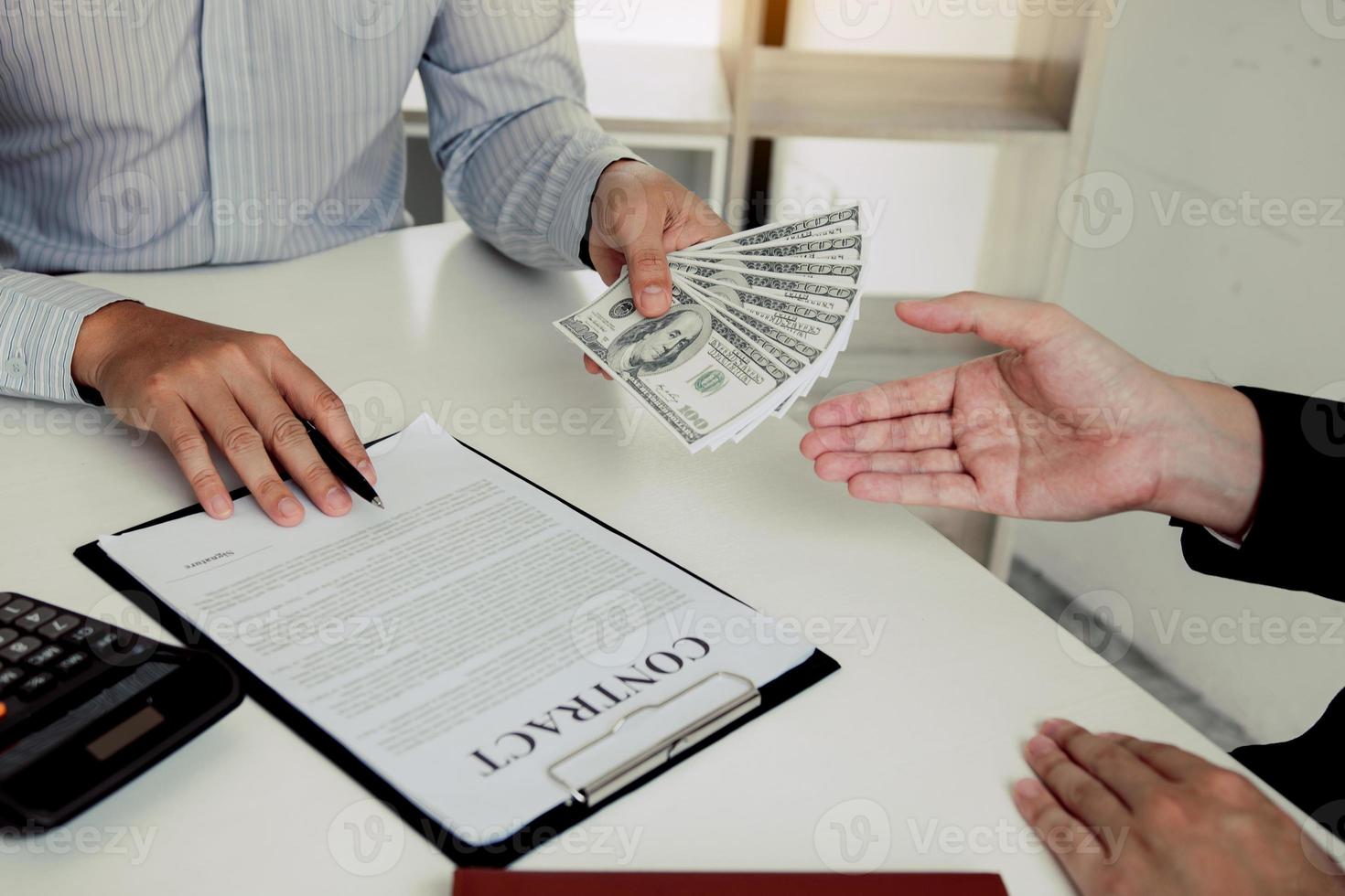 Money in the hands of businessmen who are submitting to entrepreneurs to force the signing of contract documents about corruption concept. photo