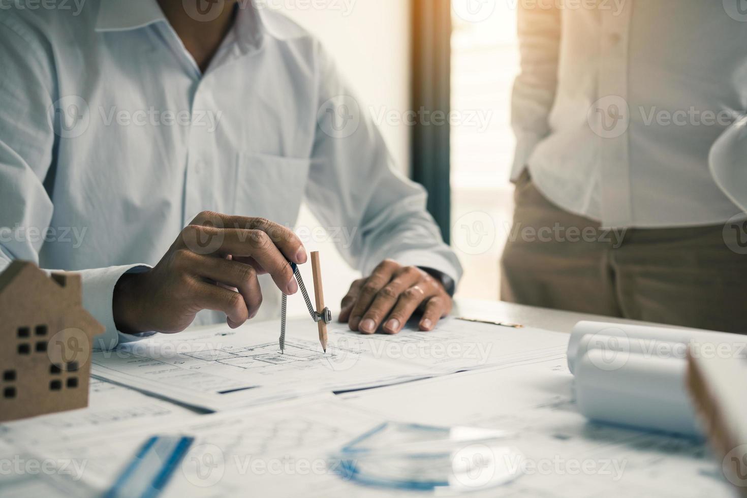 Two architect working at construction site and compass drawing pointing on blueprint with partnership. photo