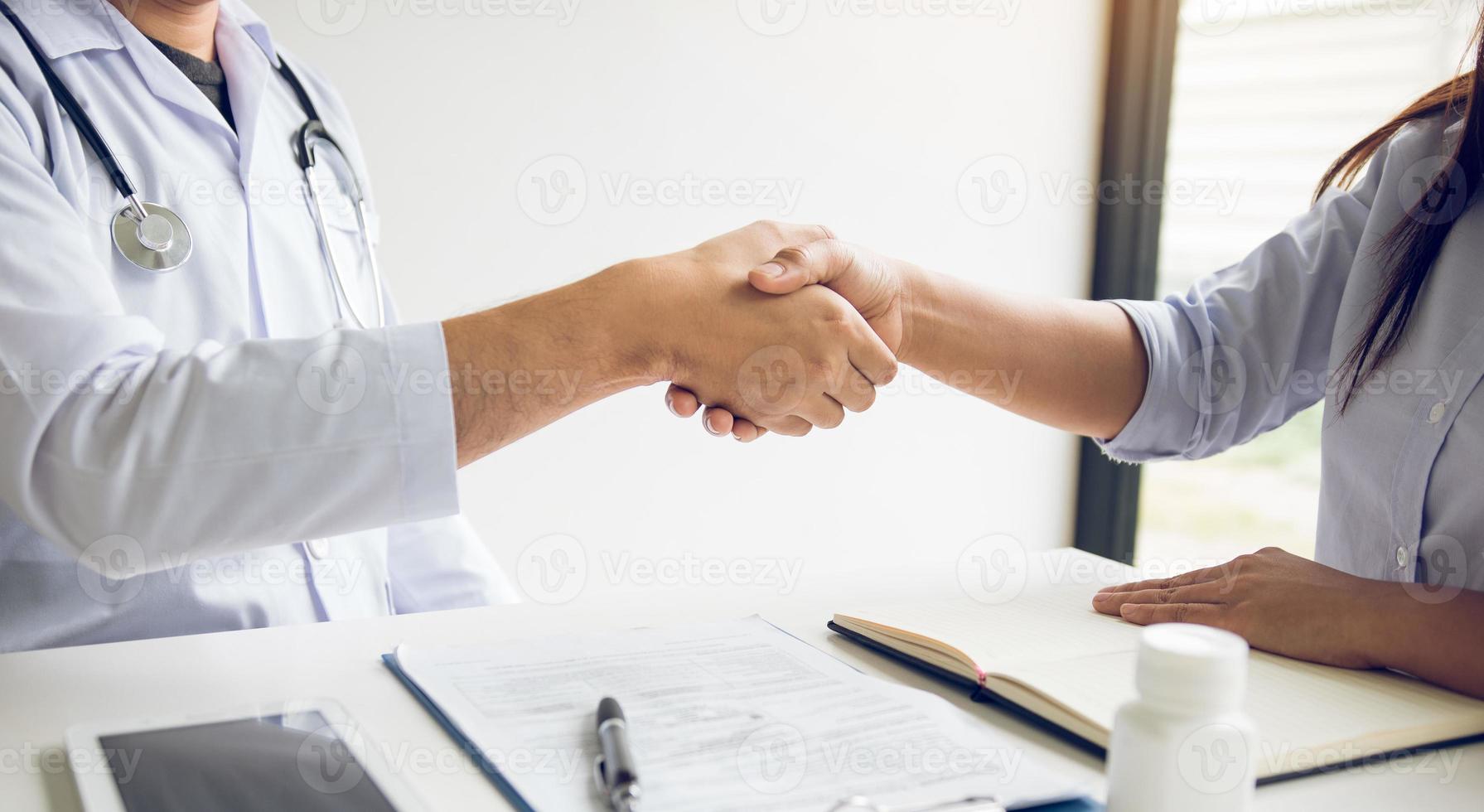 Doctor shaking hands with older patient in the clinic room. photo