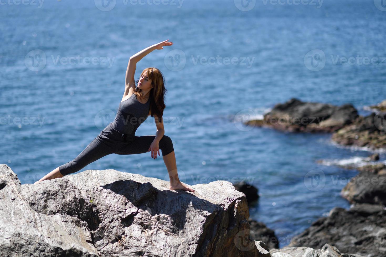 Young woman doing yoga in the beach photo