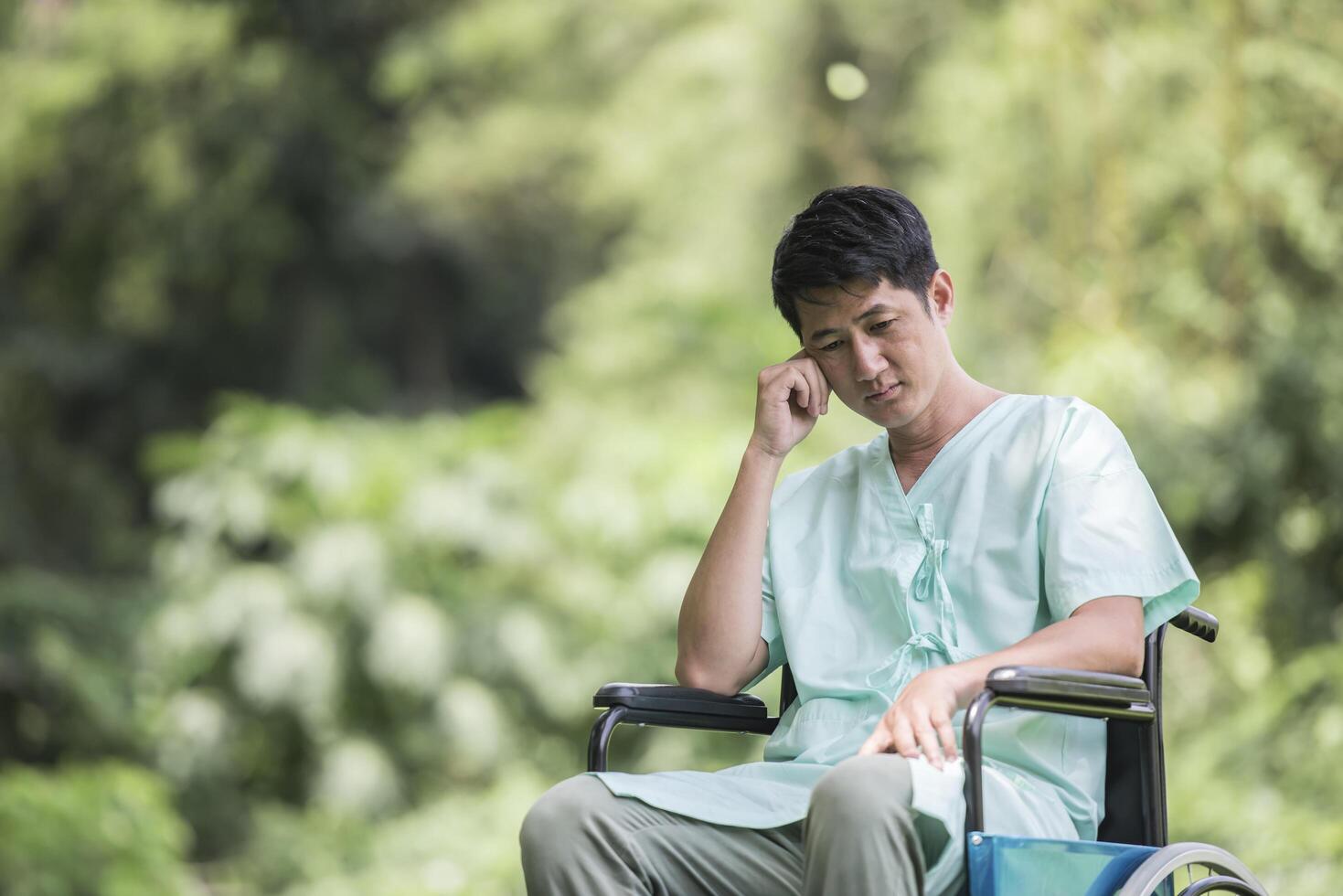 Alone young disabled man in wheelchair at the garden photo