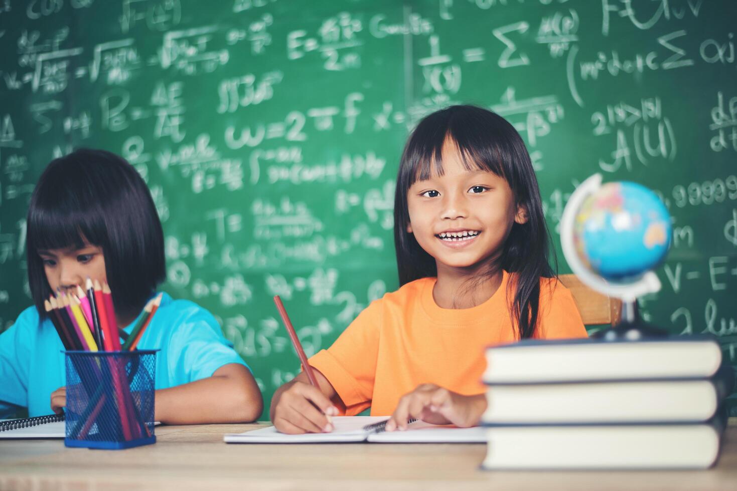 Two girl with crayon drawing at lesson in the classroom photo