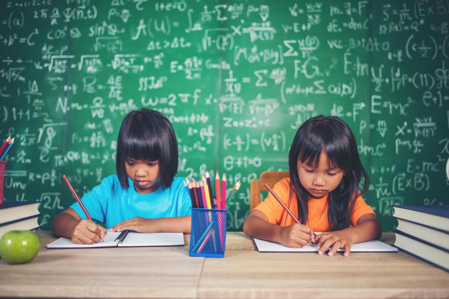 Two girl with crayon drawing at lesson in the classroom photo