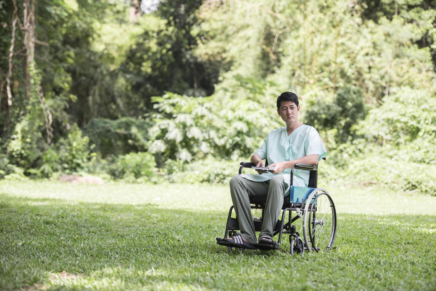 Alone young disabled man in wheelchair at the garden photo