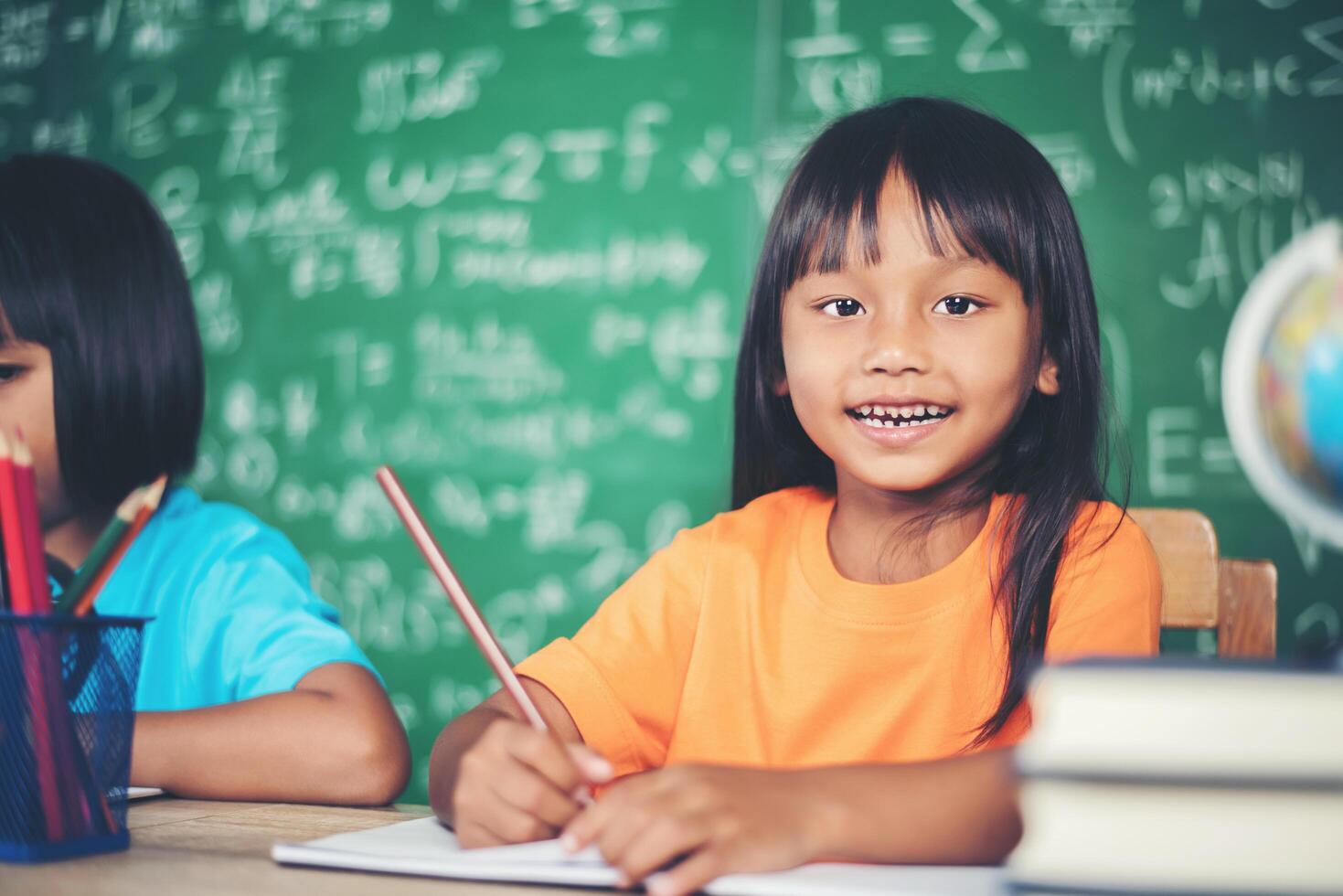Two girl with crayon drawing at lesson in the classroom photo