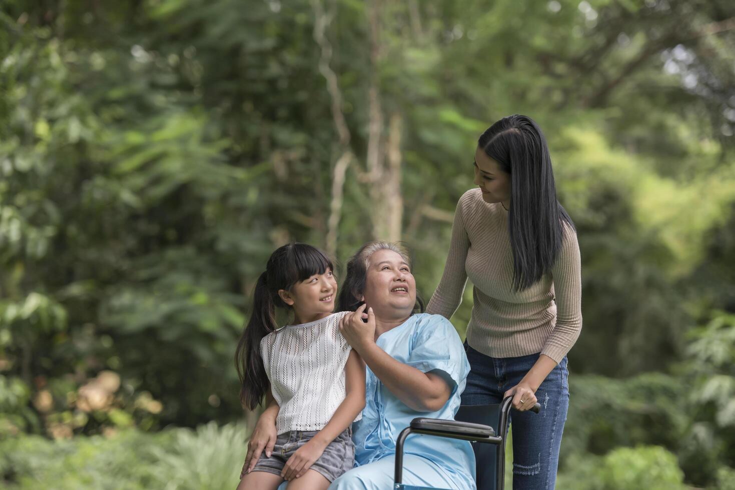 abuela feliz en silla de ruedas con su hija y nieto en un parque, vida feliz tiempo feliz. foto