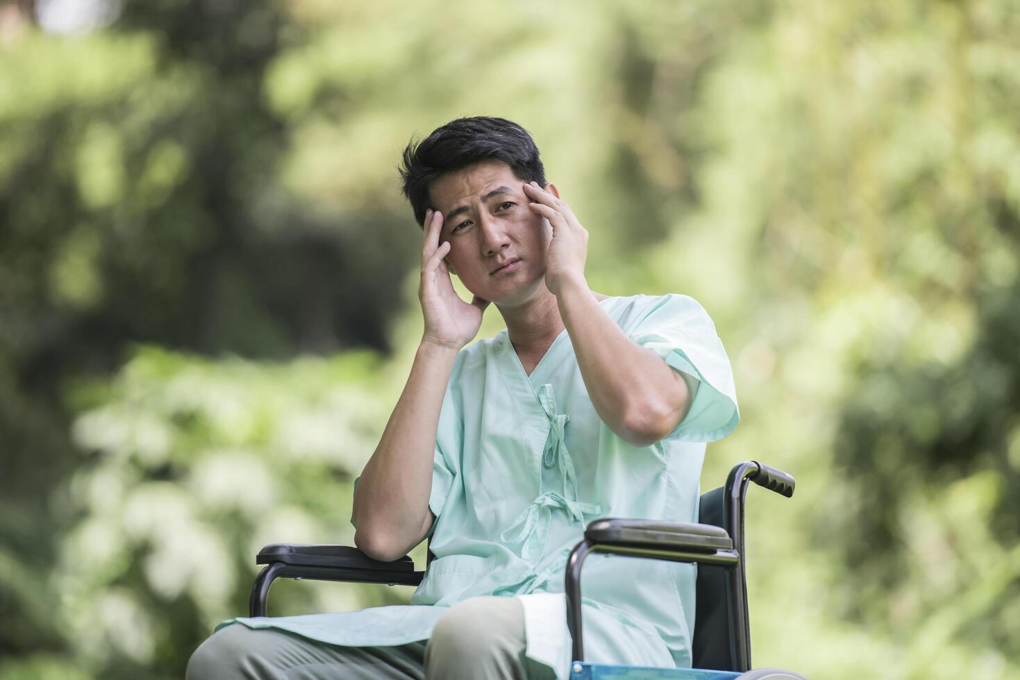 Alone young disabled man in wheelchair at the garden photo