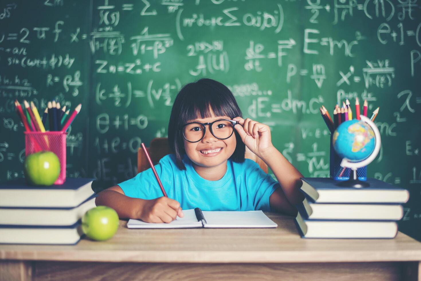 Thoughtful little girl with book near a school board photo