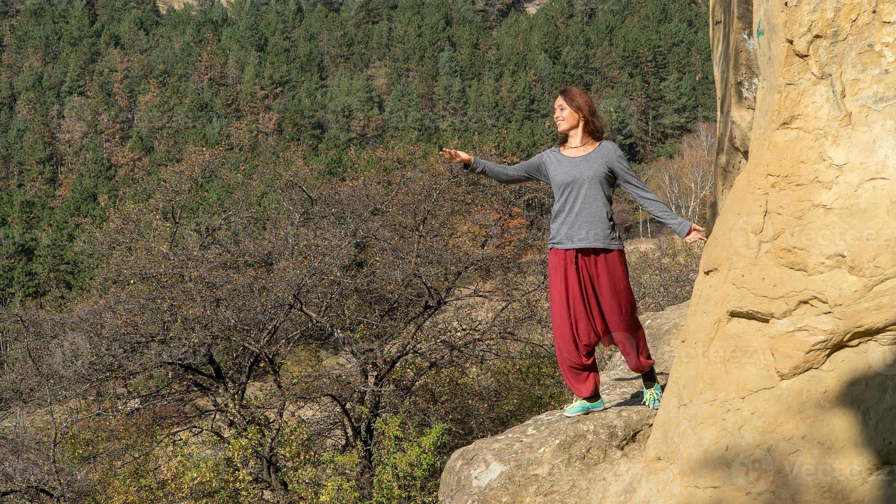 mujer frente al sol en una montaña, vestida con pantalones indios, practicando yoga, retrato en un día de otoño foto