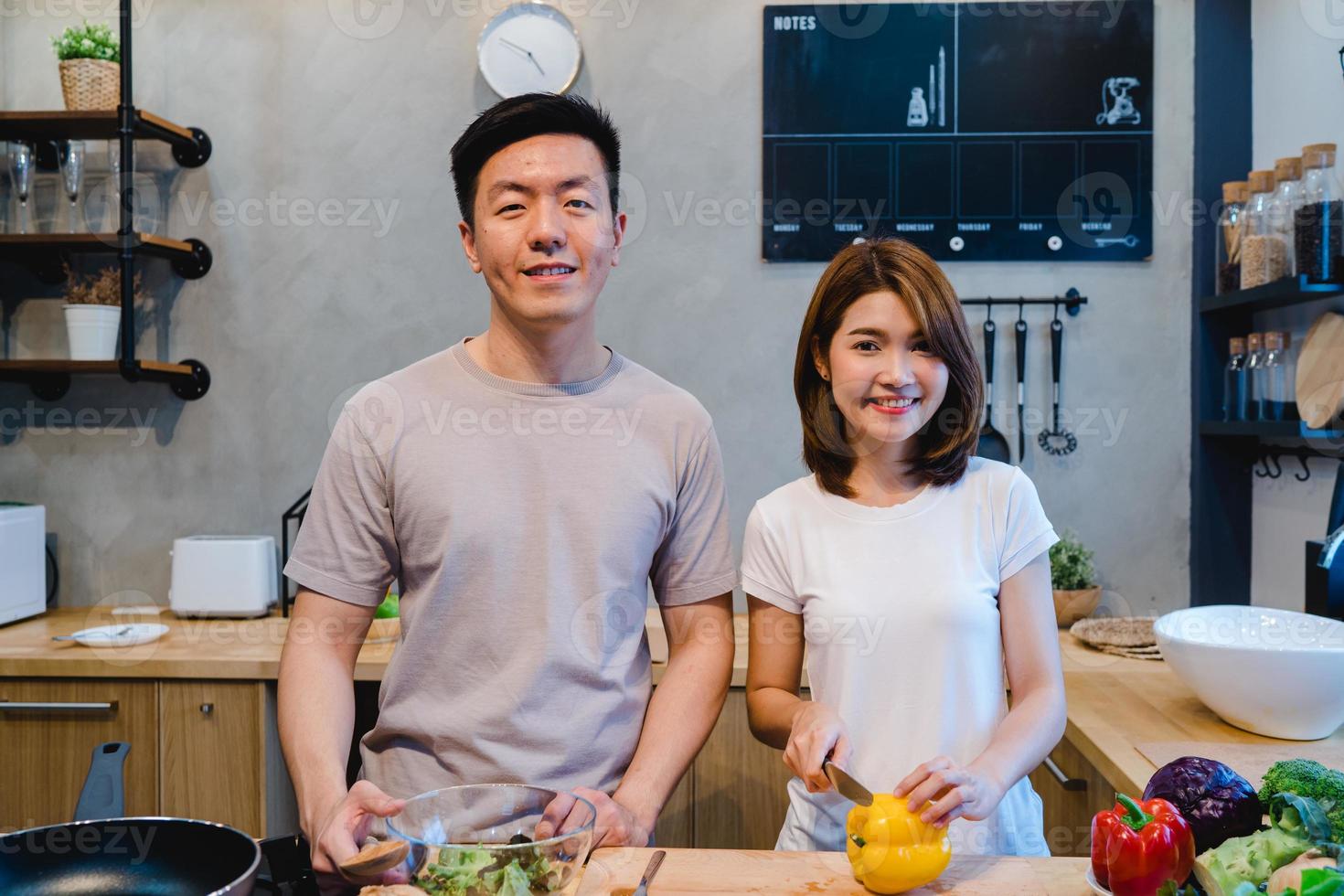 Asian couple prepare food together. Beautiful happy asian man and woman are cooking in the kitchen. Young asian couple have romantic time while staying at home. Couple lifestyle at home concept. photo