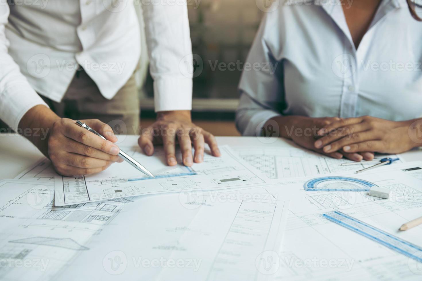 Two architect working at construction site and compass drawing pointing on blueprint with partnership. photo