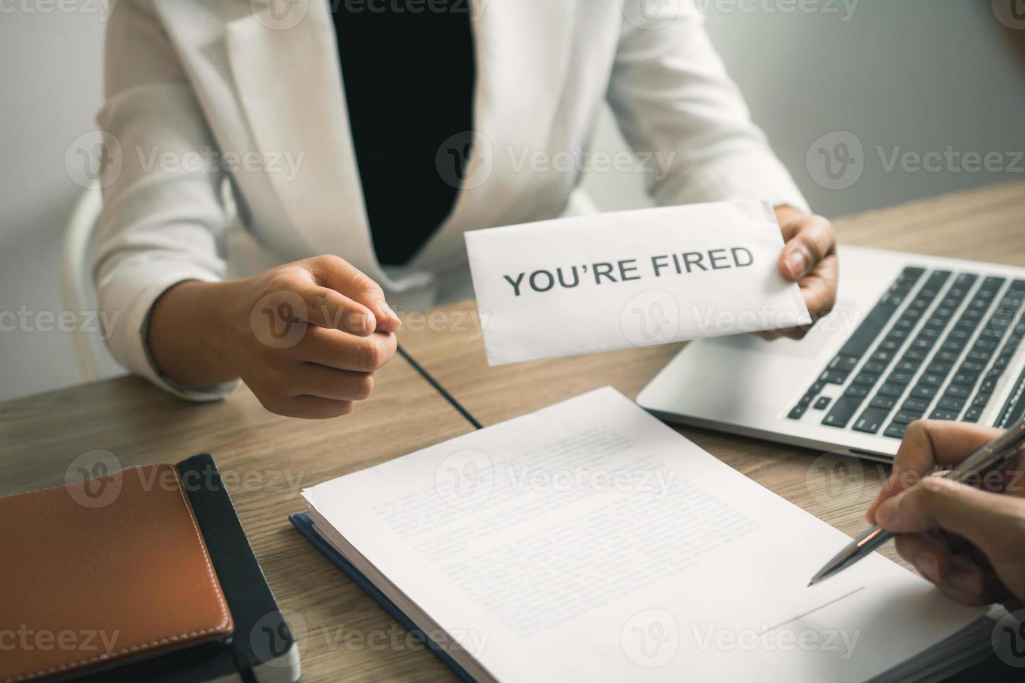 Female manager handed out the dismissal certificate to the male employee while signing the contract to quit from or resign. photo