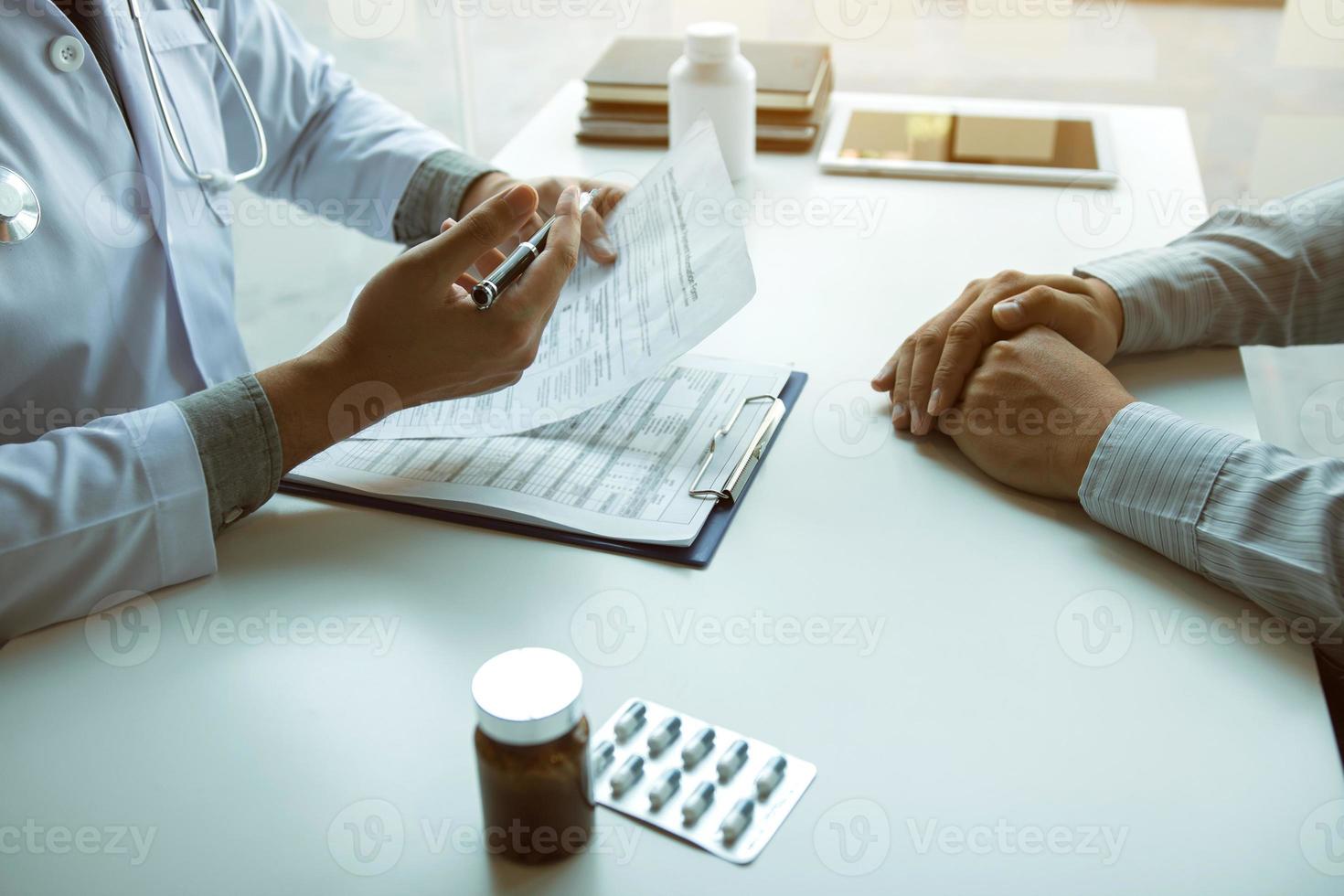 mano del médico sosteniendo la pluma escribiendo la lista de antecedentes del paciente en el bloc de notas y hablando con el paciente sobre la medicación y el tratamiento. foto