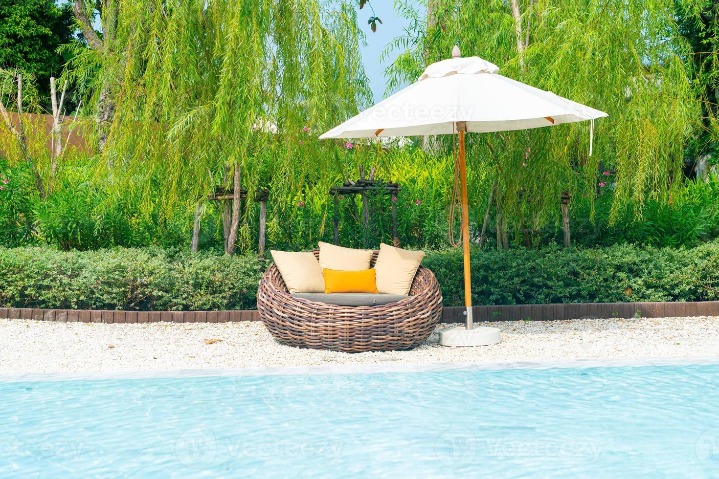 outdoor patio chair with pillow and umbrella around swimming pool photo