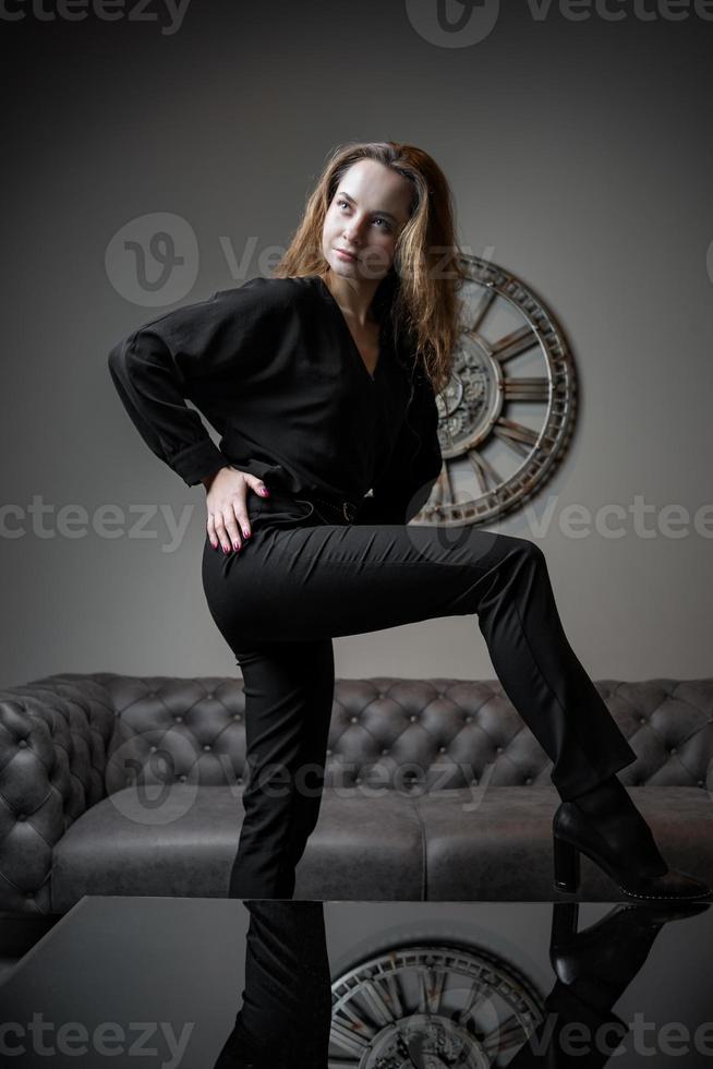 chica y tiempo. hermosa joven posando contra el fondo de un reloj de pared foto