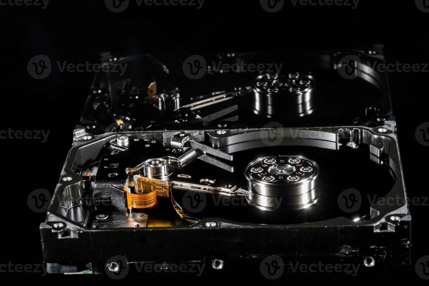 Disassembled and opened hard disk drive, inside view with reflections, isolated on black photo