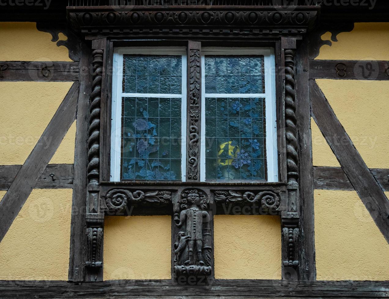 Classic Alsatian windows in a half-timbered house, decorated with wooden carvings and flowers photo