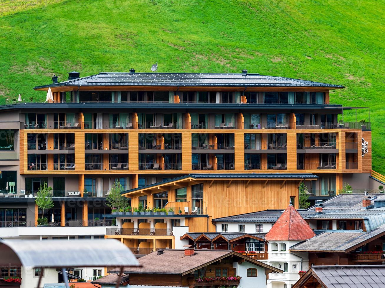 colinas verdes de un resort alpino en austria en verano. pequeño pueblo, hoteles y chalets, todo en colores. hermosas terrazas y paneles solares en los techos. la proximidad de la civilización y la naturaleza pura. foto