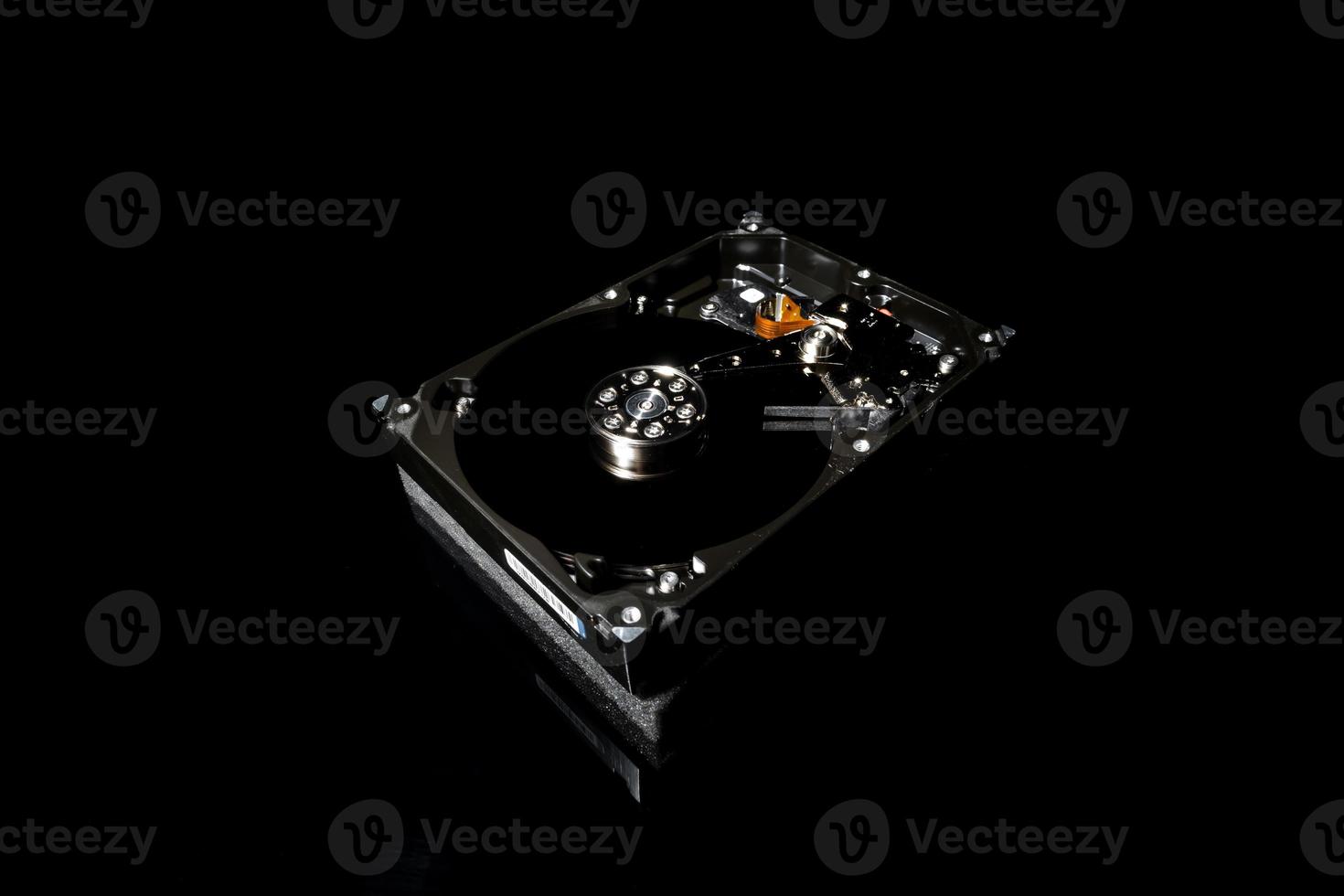 Disassembled and opened hard disk drive, inside view with reflections, isolated on black photo