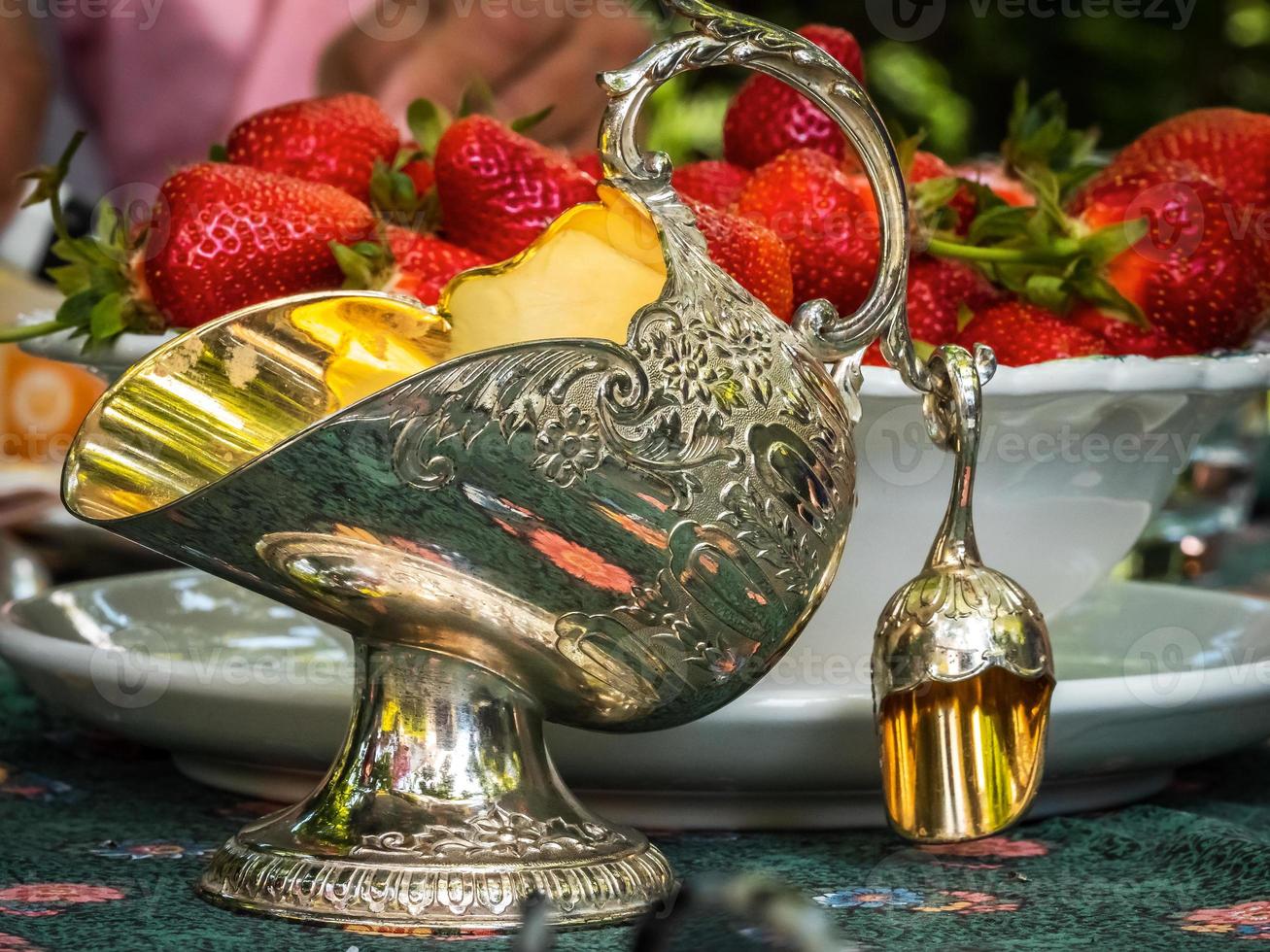 Silver sugar bowl in the shape of a basket for coal. Antique item for the table. Elegant rich dishes for decorating a feast. Strawberries for dessert. photo