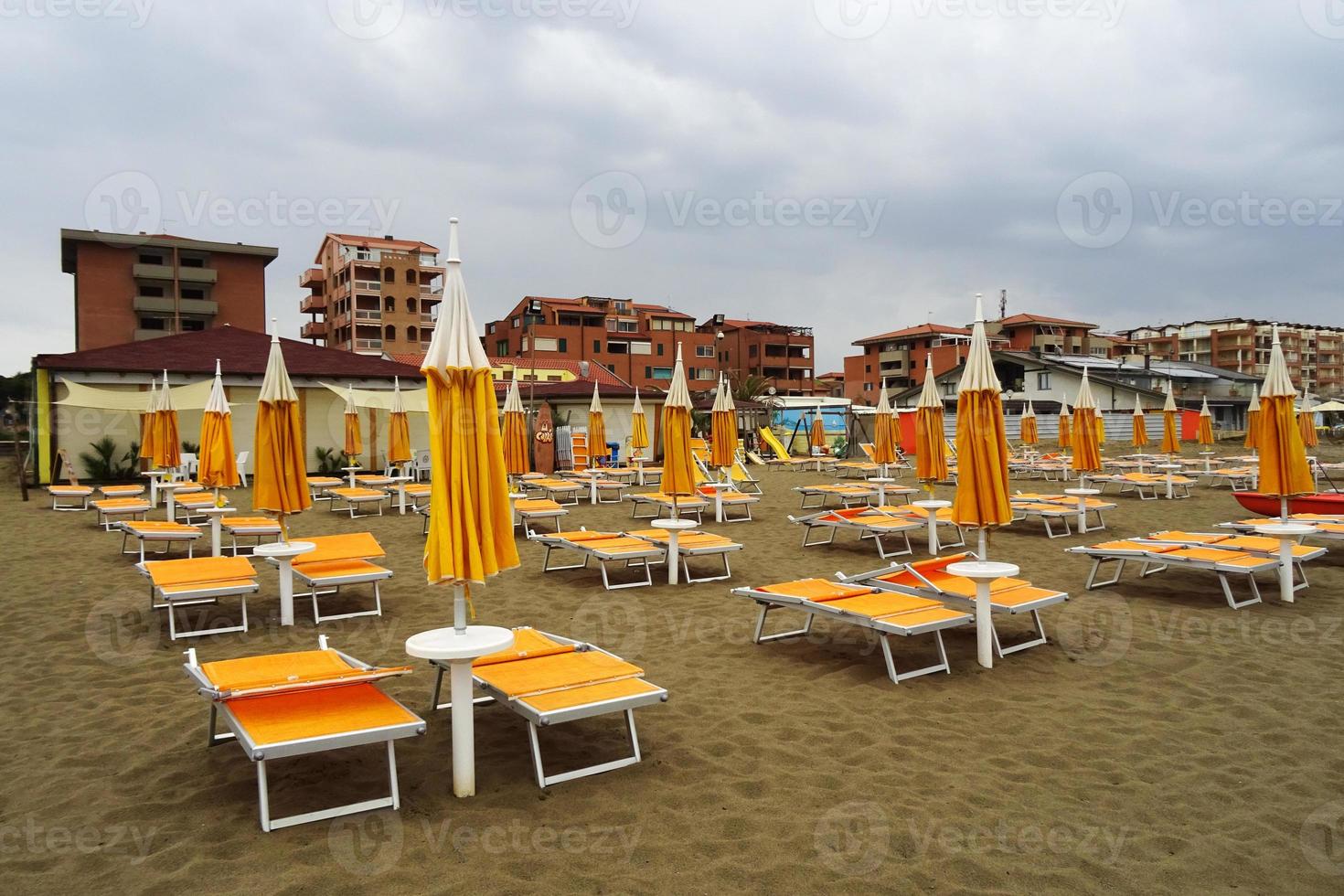 Lined up sunbeds on a deserted beach on a cloudy day. Tuscany photo