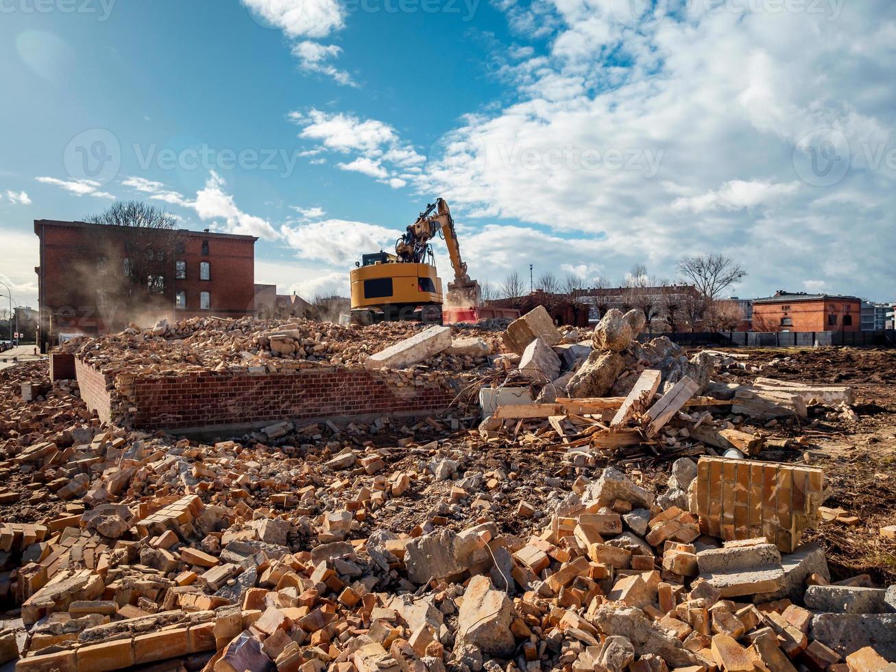 An excavator breaks down an old building. Dust, bricks and broken walls. photo