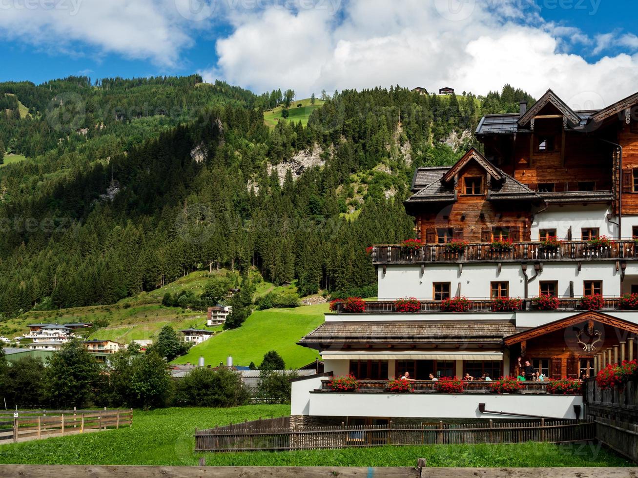 colinas verdes de un resort alpino en austria en verano. pequeño pueblo, hoteles y chalets, todo en colores. hermosas terrazas y paneles solares en los techos. la proximidad de la civilización y la naturaleza pura. foto