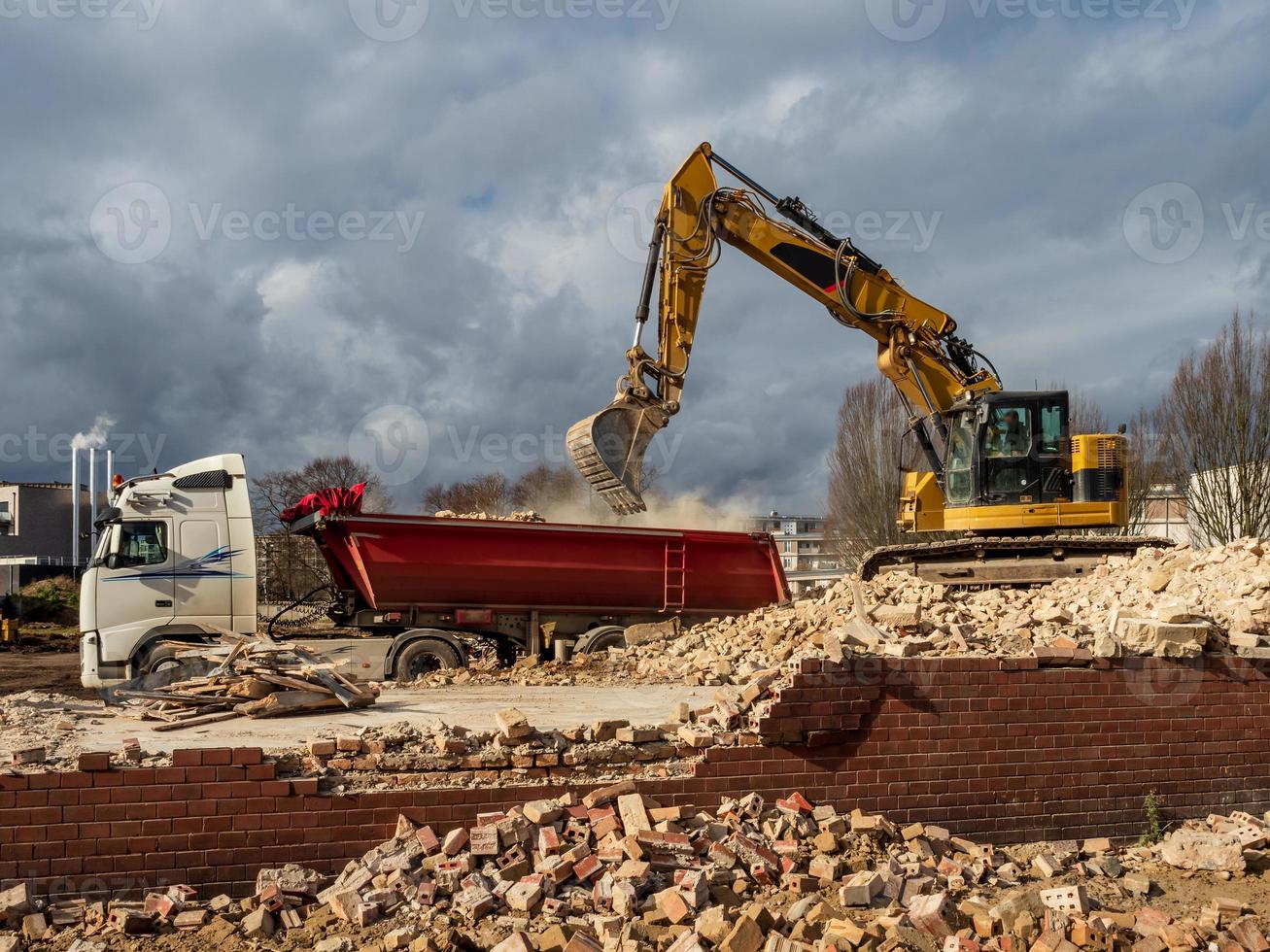 An excavator breaks down an old building. Dust, bricks and broken walls. photo