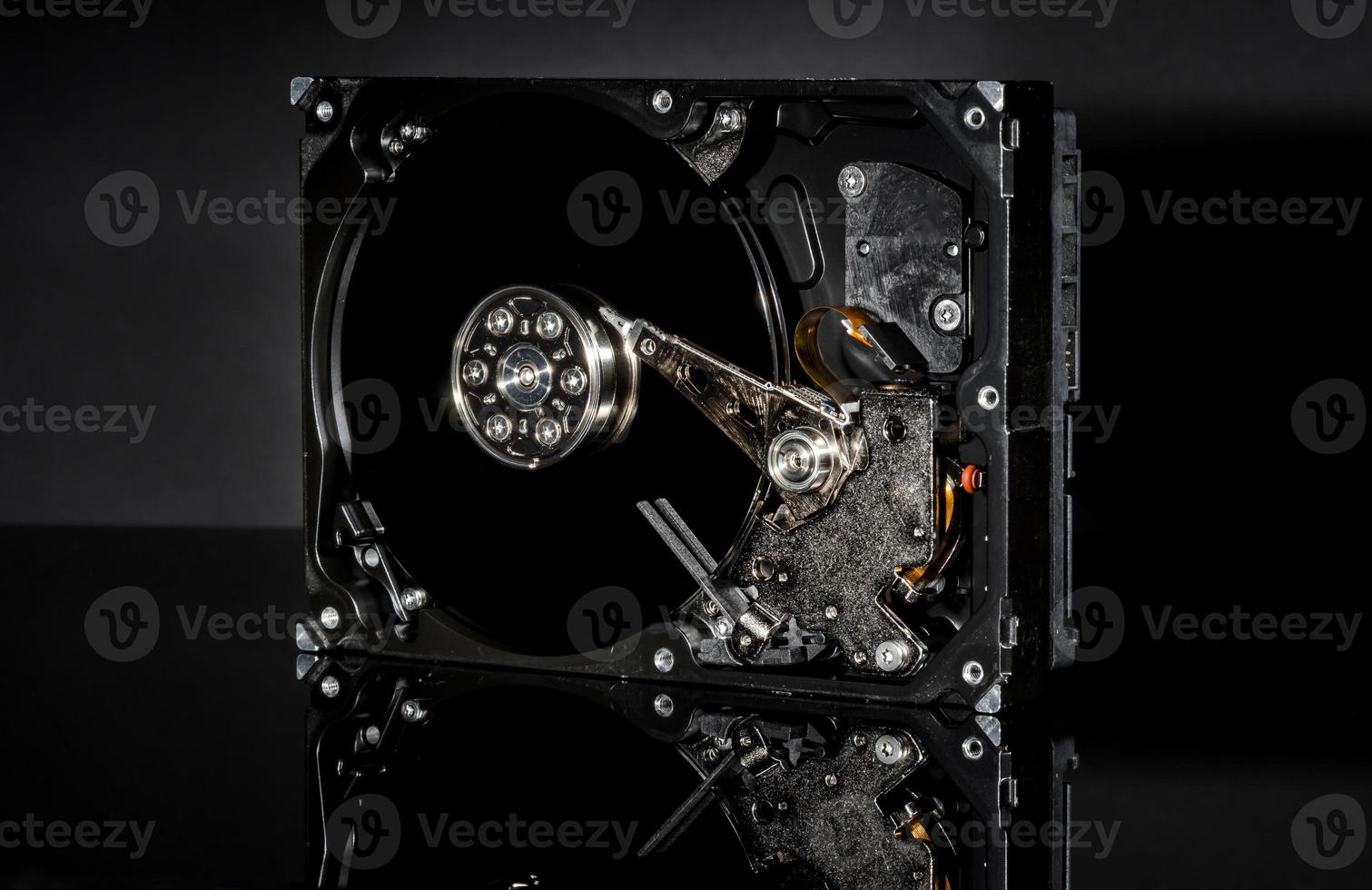 Disassembled and opened hard disk drive, inside view with reflections, isolated on black photo