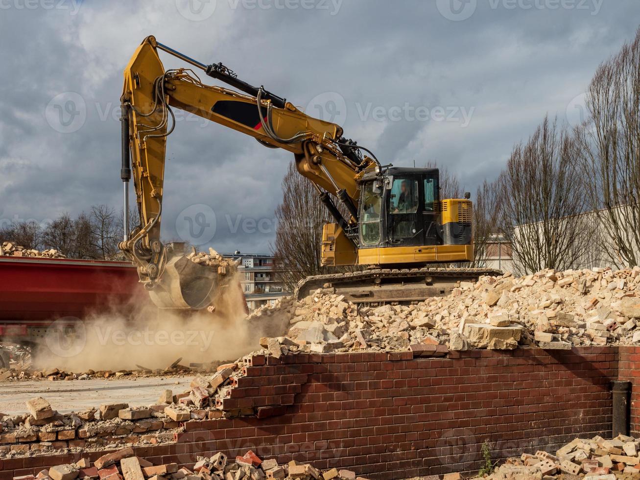 An excavator breaks down an old building. Dust, bricks and broken walls. photo