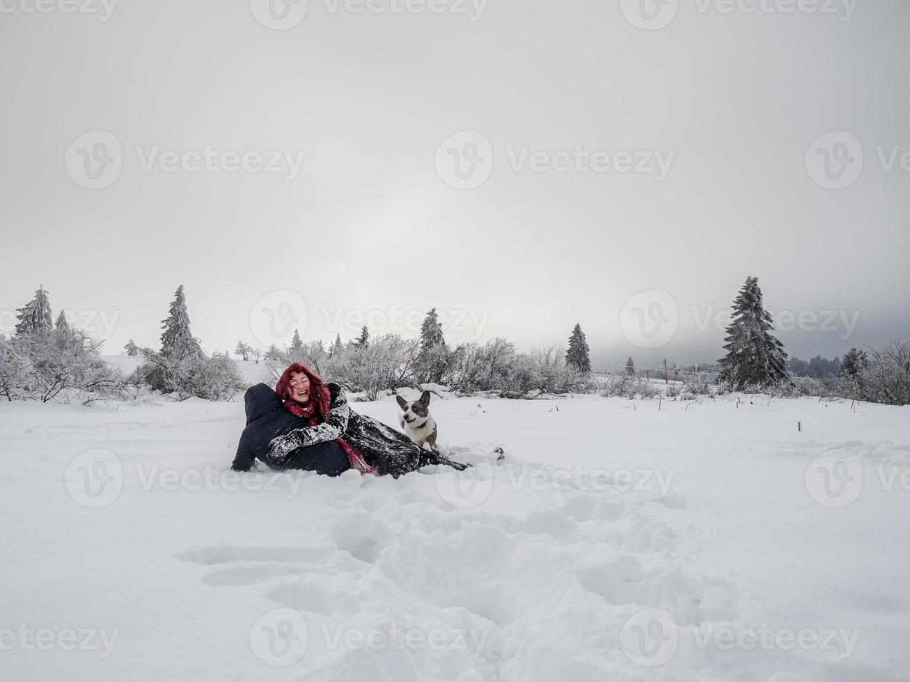 dos niñas, hermanas, juegan con un perro corgi en un campo nevado en las montañas foto