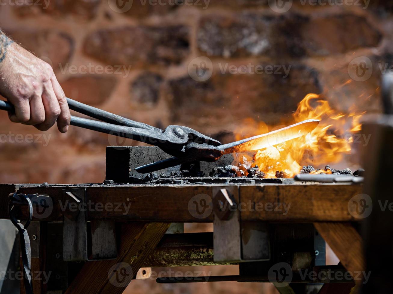 Authentic blacksmith forges metal on the anvil. Medieval traditions photo