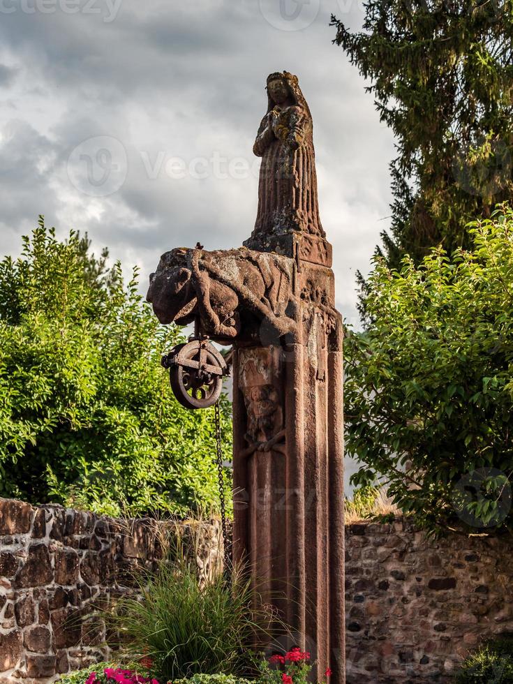 estatua de piedra medieval sobre un pozo viejo, alsacia, territorio de la abadía de andlau foto