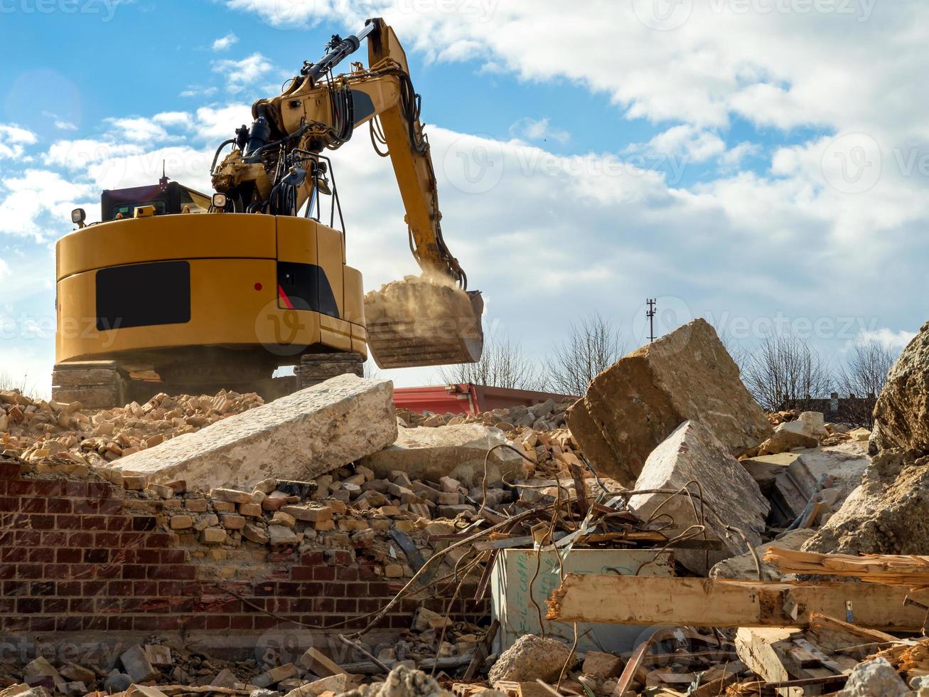 An excavator breaks down an old building. Dust, bricks and broken walls. photo