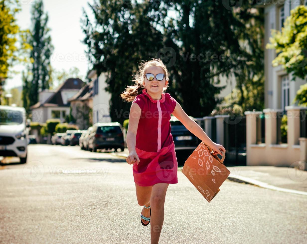 Emotional photos of a schoolgirl girl who runs along the street in the bright sun.