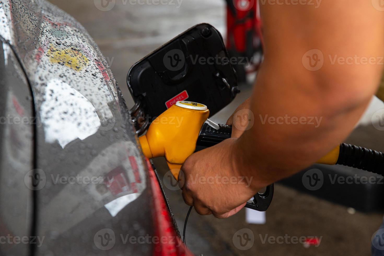 Man filling gasoline fuel in car holding pump. photo