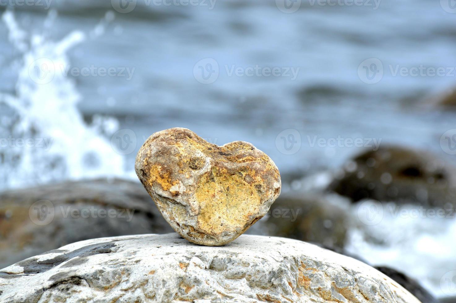Heart shape stone against background of beach. Summer sunny day. Love, wedding and Valentine day concept. Finding beautiful and interesting stones. Beach vacation photo