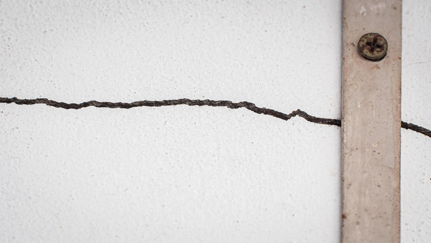 Cracks on the wall. The crack in the cement wall at the window sill, caused by the subsidence of the ground, causing a slit at an oblique angle. photo