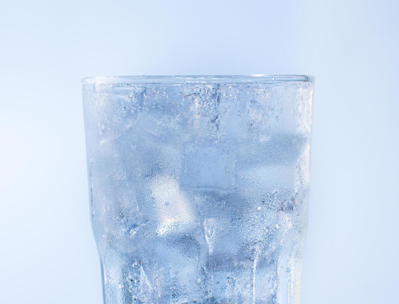 un vaso de agua transparente para bebidas frías. gotas de hielo y agua se adhieren al borde del vaso. agua de soda con cubitos de hielo foto