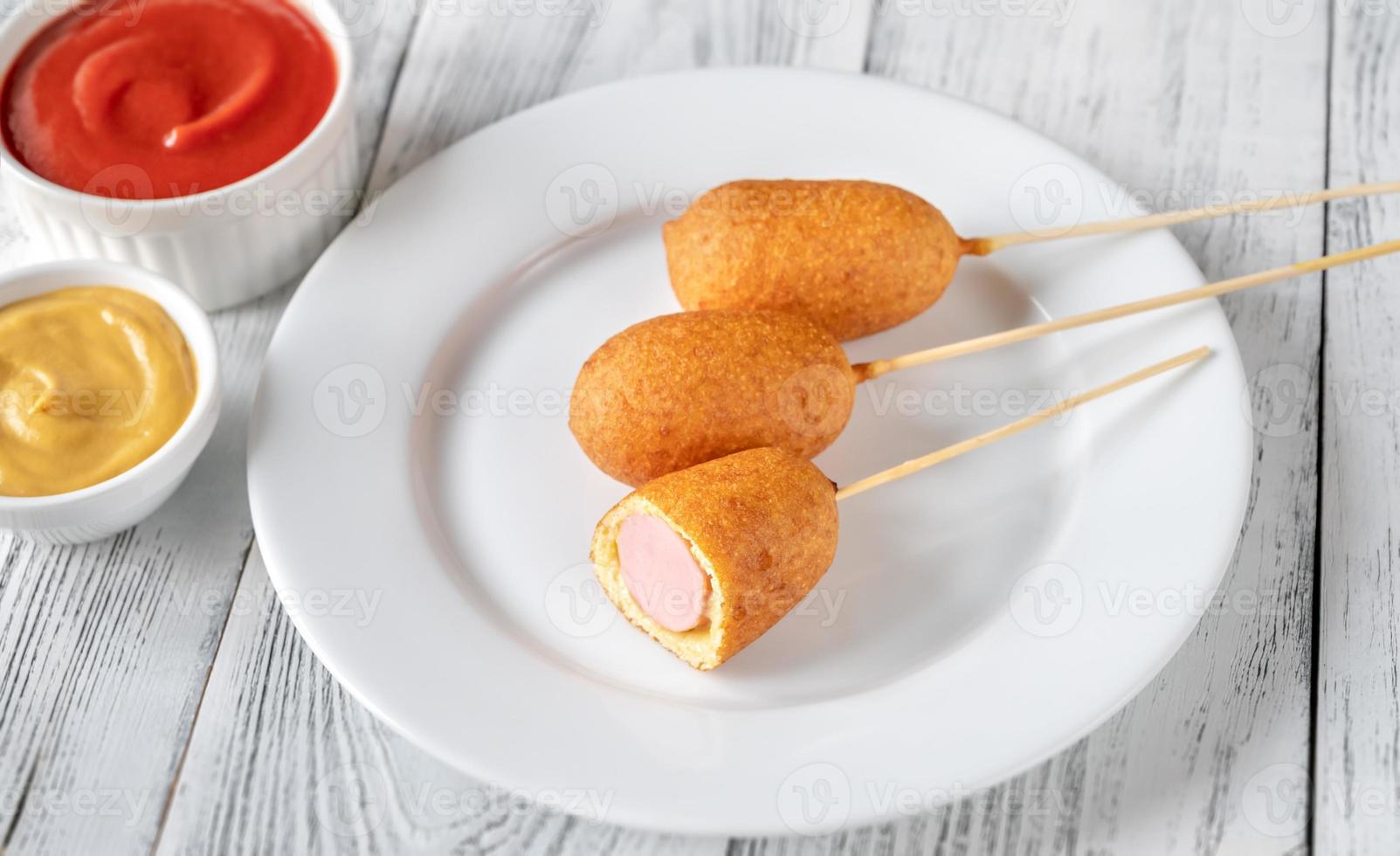 Corn dogs on white serving plate photo