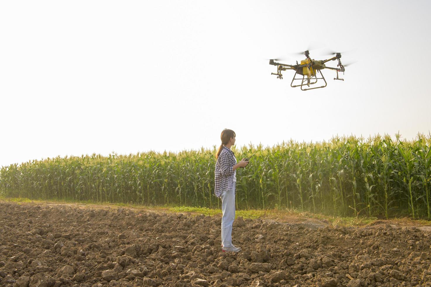 Young smart farmer controlling drone spraying fertilizer and pesticide over farmland,High technology innovations and smart farming photo