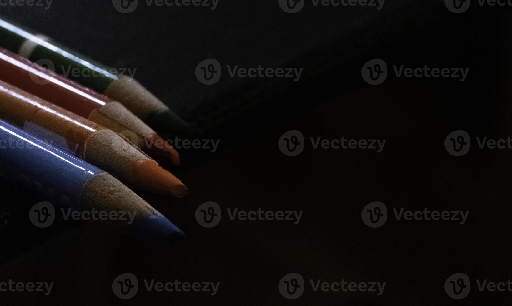 a group of colored pencils ,crayons, on a black background that highlights the colors of the crayons photo