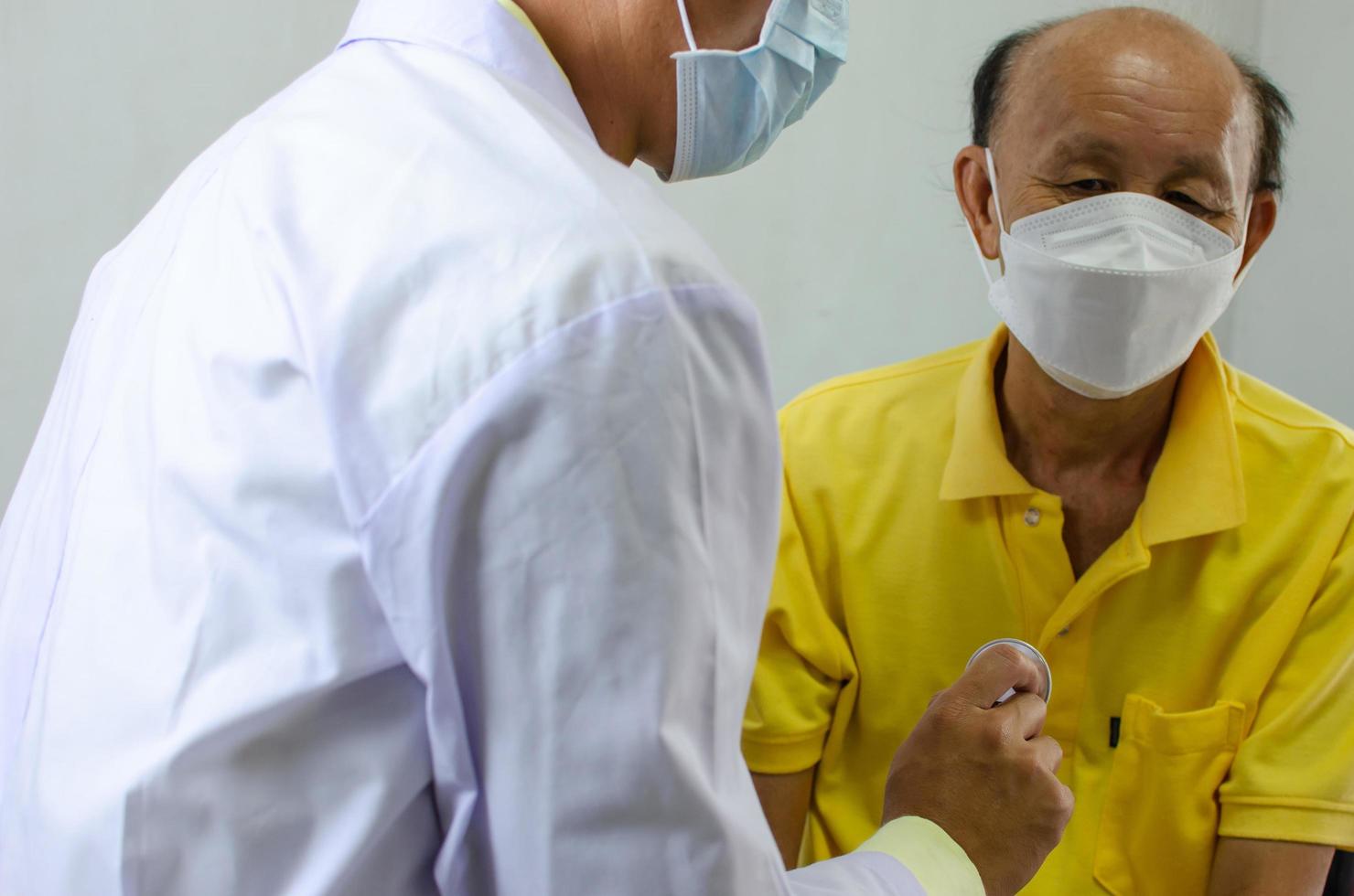 doctor checks the heartbeat of an elderly man photo