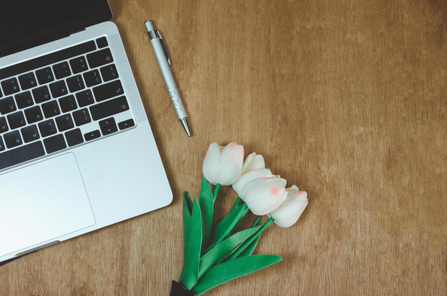 Top view flat lay computer laptop and flower on wood table.Copy space photo