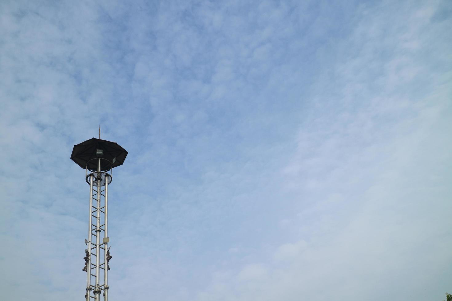 a high lamppost under a bright cloud photo