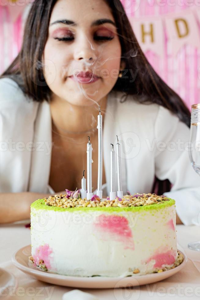 mujer con ropa de fiesta blanca preparando una mesa de cumpleaños pidiendo un deseo foto