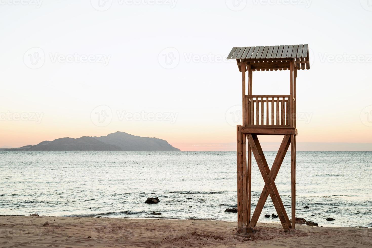 seguridad de salvavidas en la playa. puesto de salvavidas de madera en la playa de arena al amanecer foto